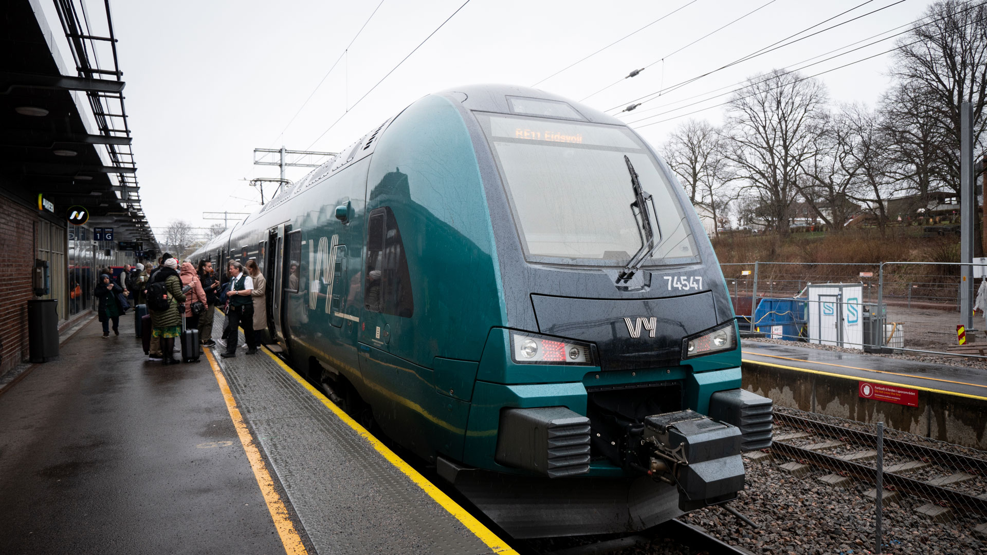 Tog med passasjerer på perrongen