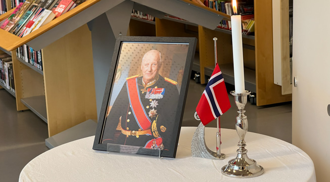 Bord med bilde av Kong Harald, flagg og lys