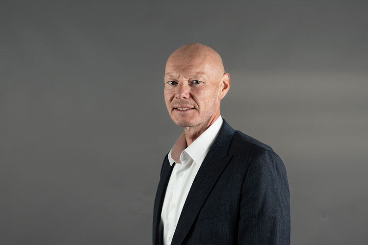 Portrett av mann i dress med grå bakgrunn