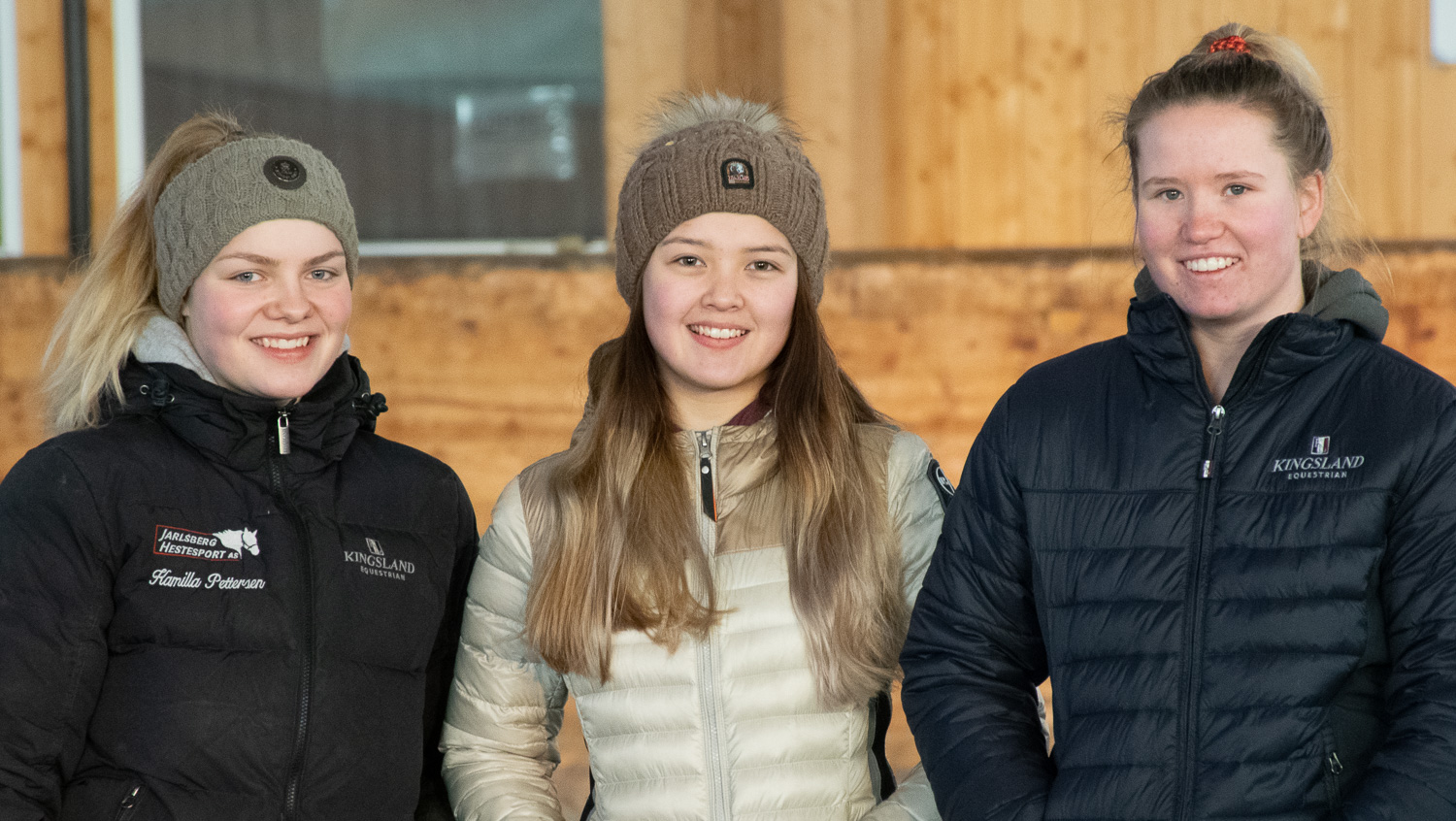 Tre glade jenter i ridehall