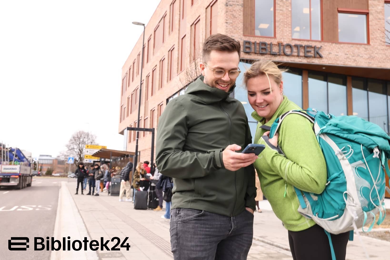 Mann og dame ser på telefonen utenfor et bibliotek