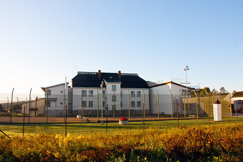 Sem fengsel Tønsberg i kveldssol. Høye gjerder foran en hvit, litt gammeldags murbygning.