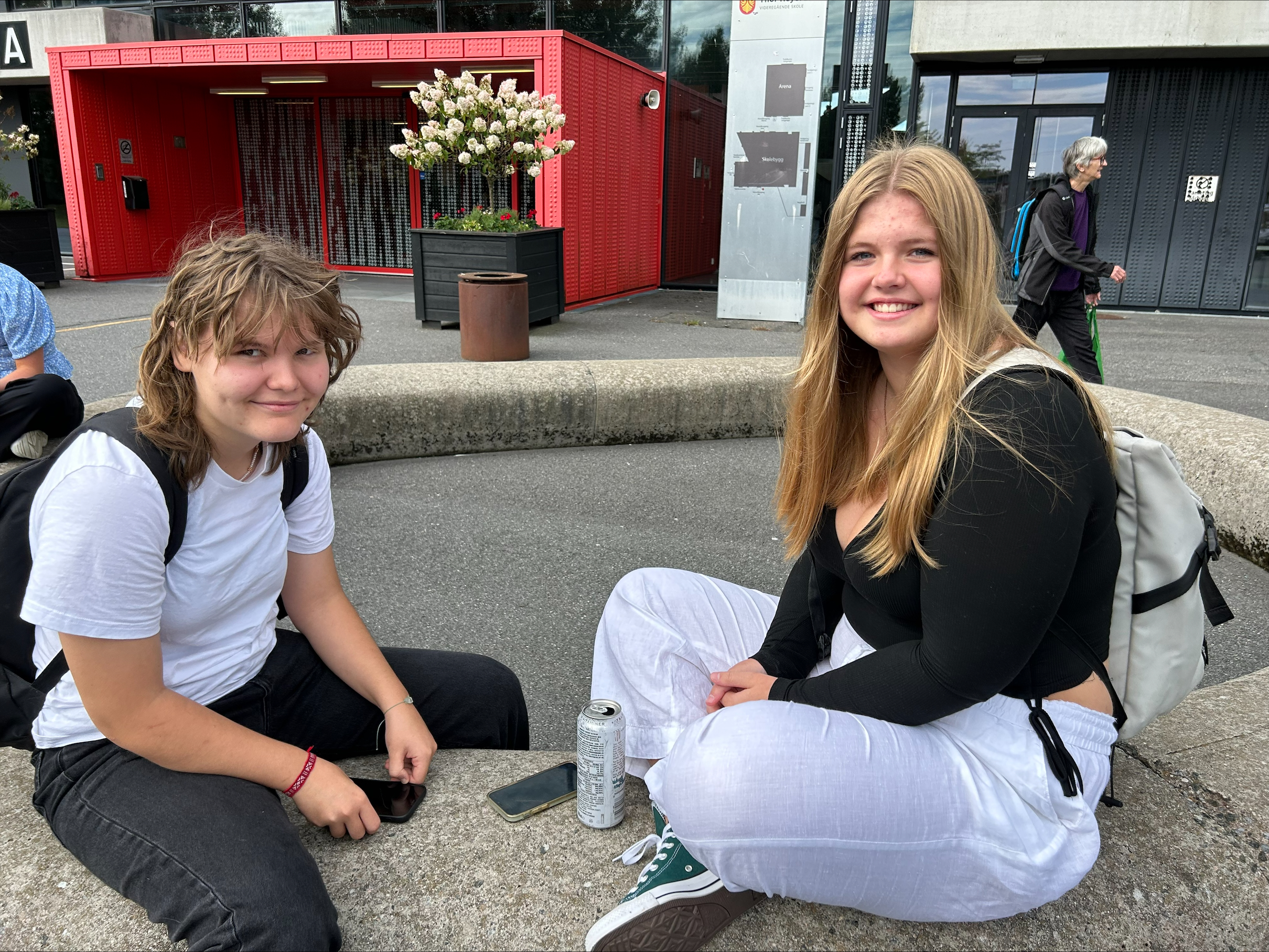 To spente elever sitter utenfor skolen første skoledag