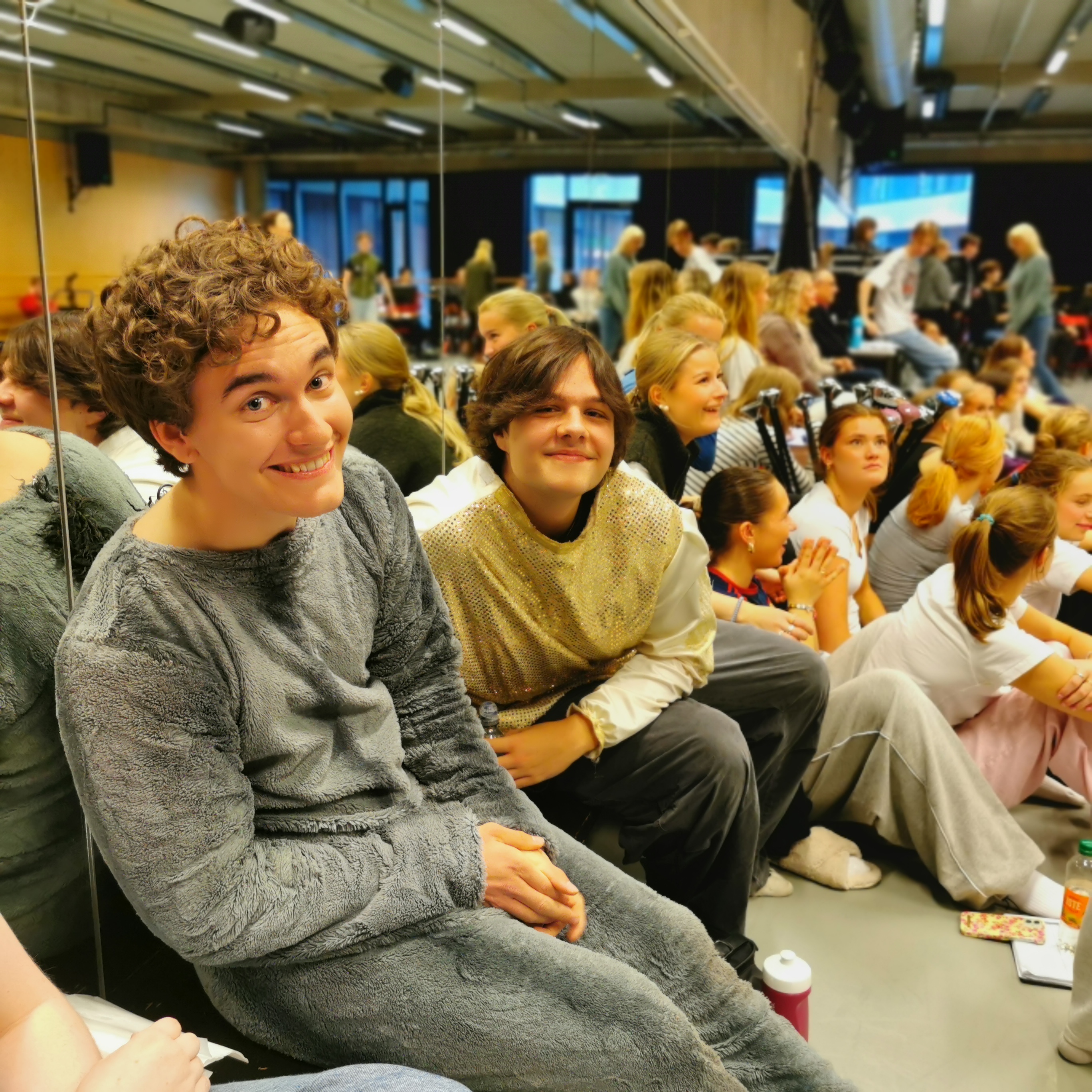 Elever i dansesalen, smilende og ser i kameraet.