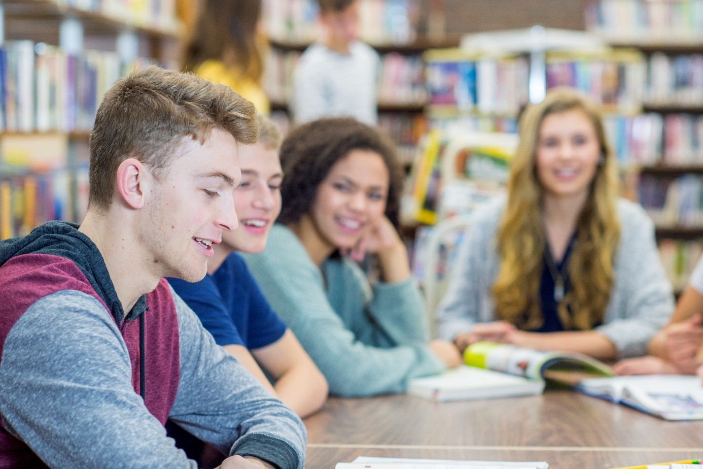 4 unge mennesker i samtale rundt et bord i et bibliotek
