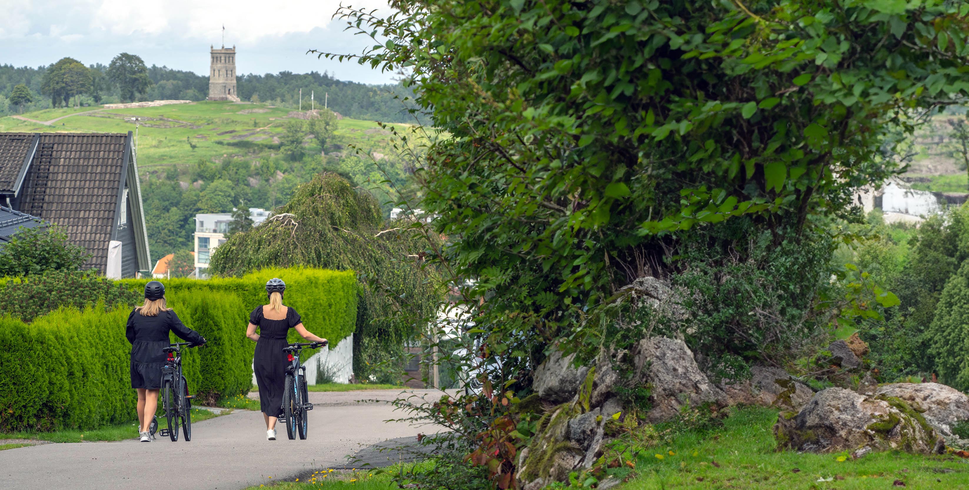 Foto av to kvinner triller sykkel i Valhalla på Kaldnes med utsikt mot Slottsfjellet