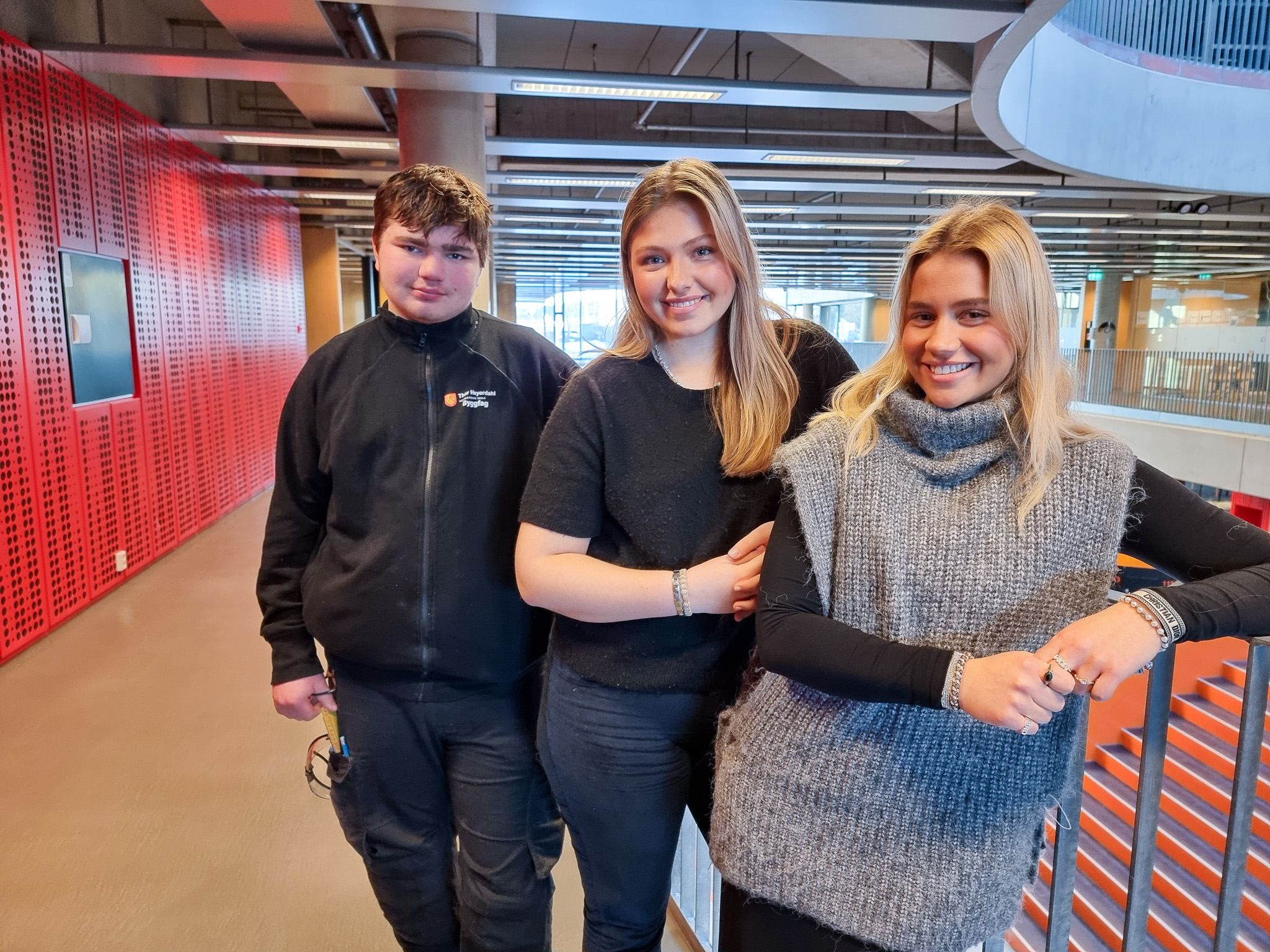 De tre elevene står sammen i skolebygget.