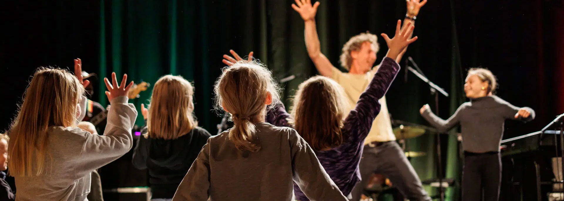 Barn foran scene med henda til væres