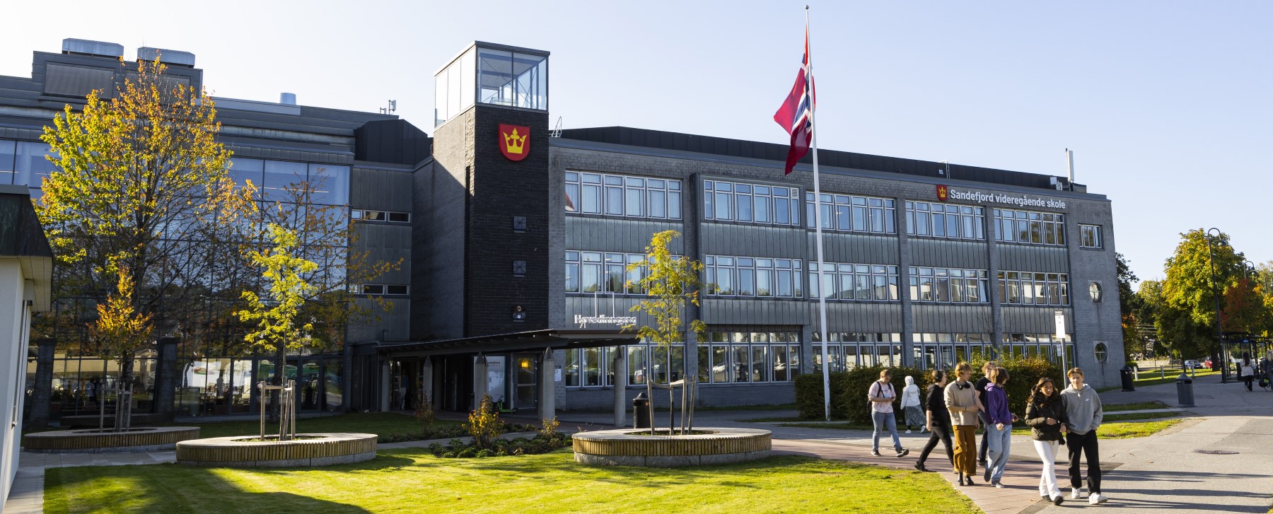 Hovedinngangen til skolen, flagget er heist til topps på flaggstangen.