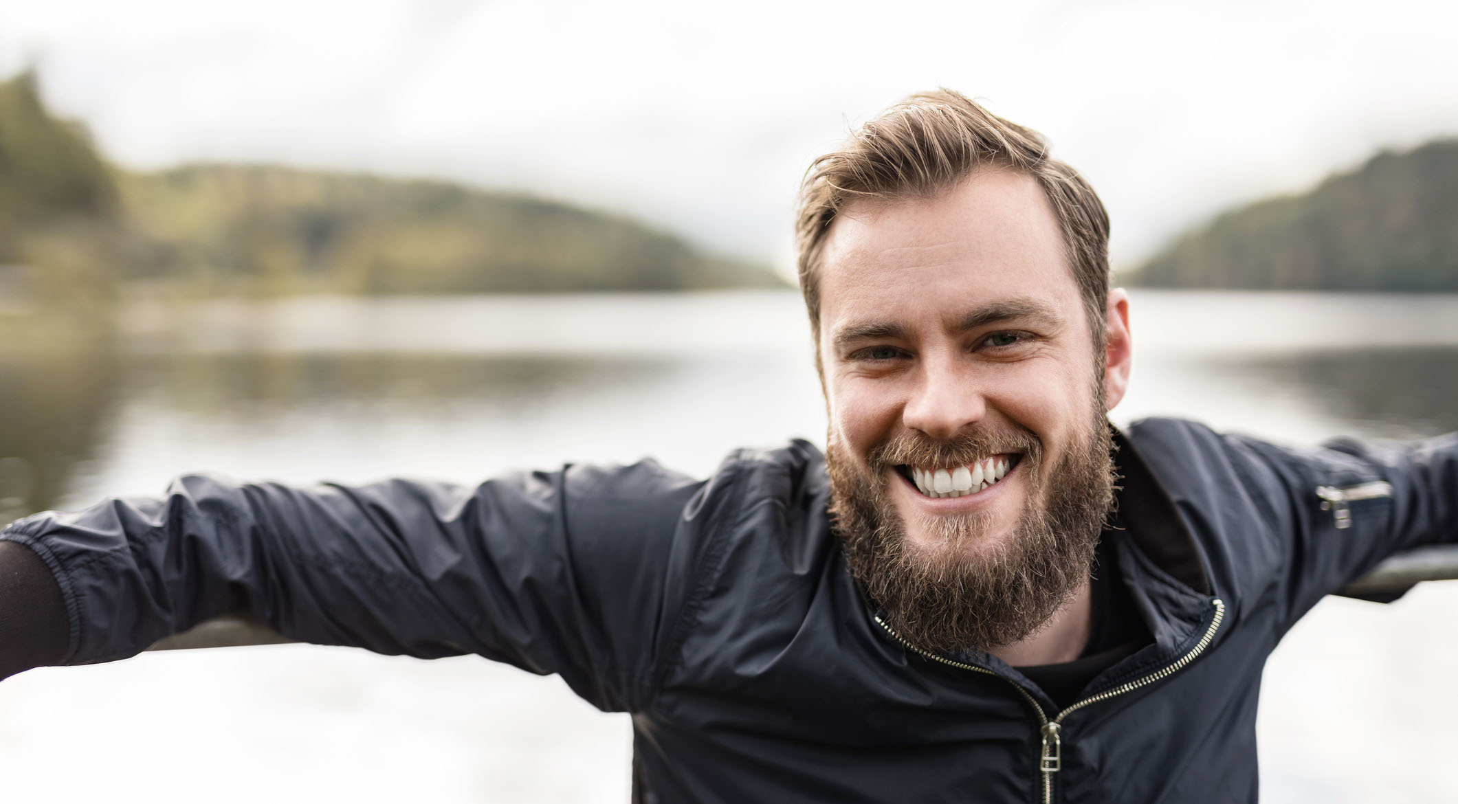 Mann med skjegg og et vann i bakgrunnen