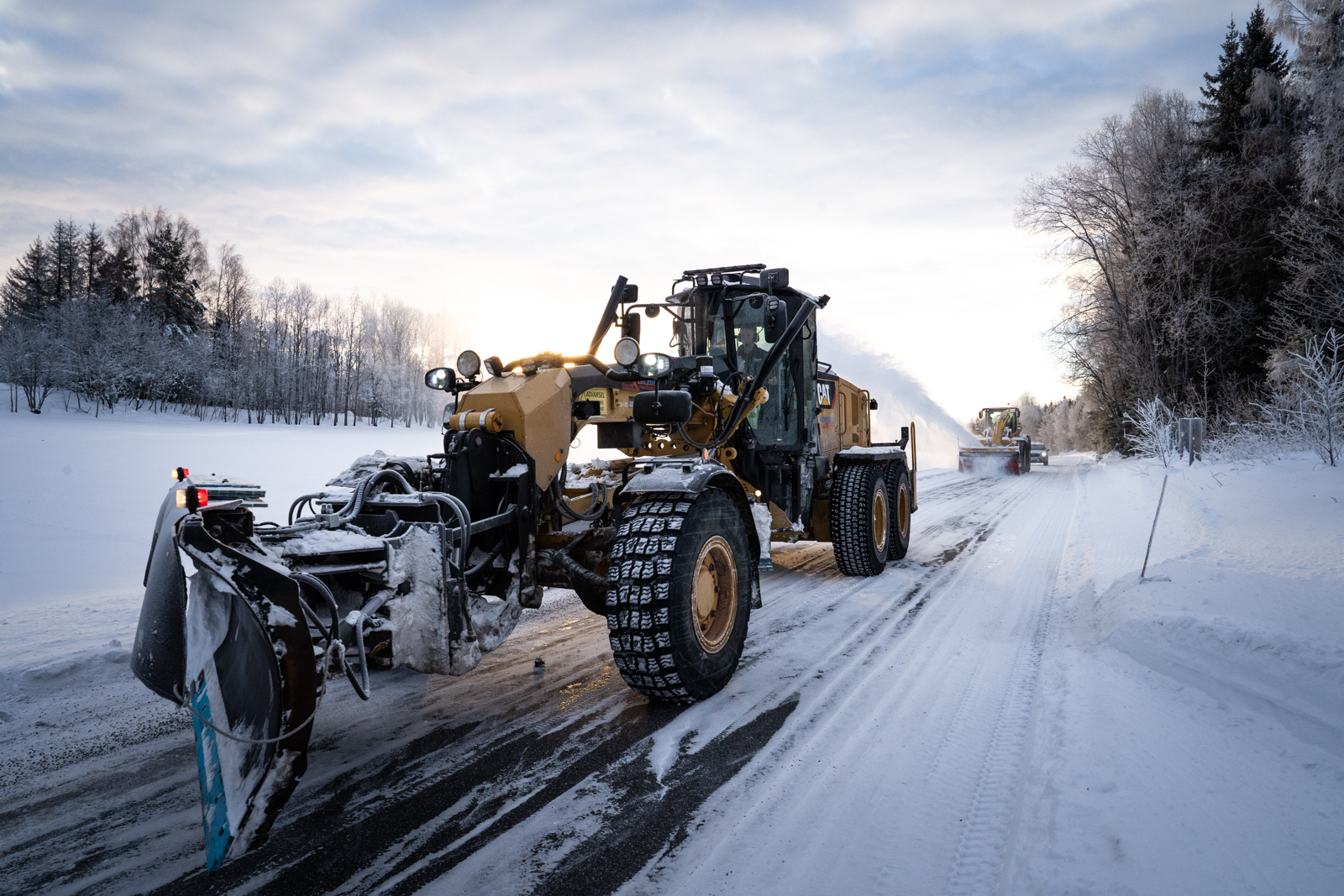 Brøytebil med snøfres jobber seg innover i bildet.