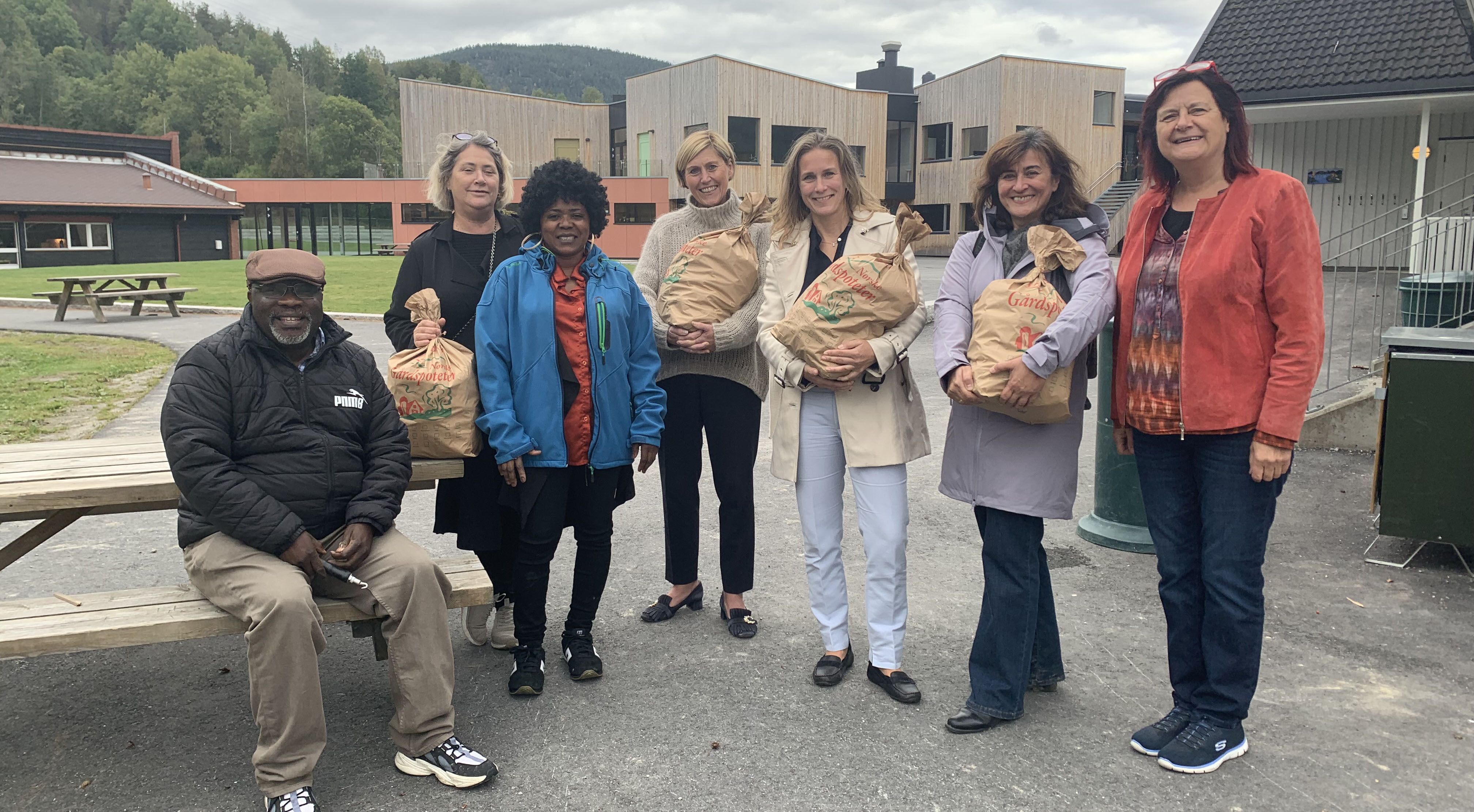 Sju personer oppstilt ute, fire med potetsekk i armene