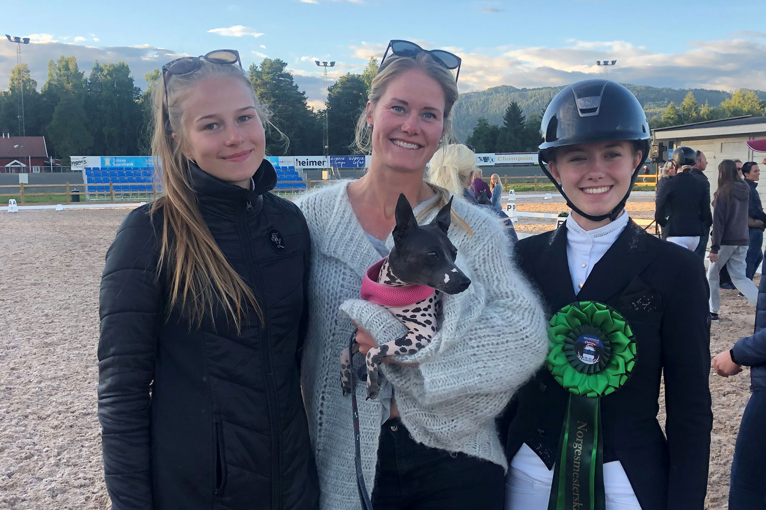 Dressurtreneren med hund på armen, flankert av to dressurelever