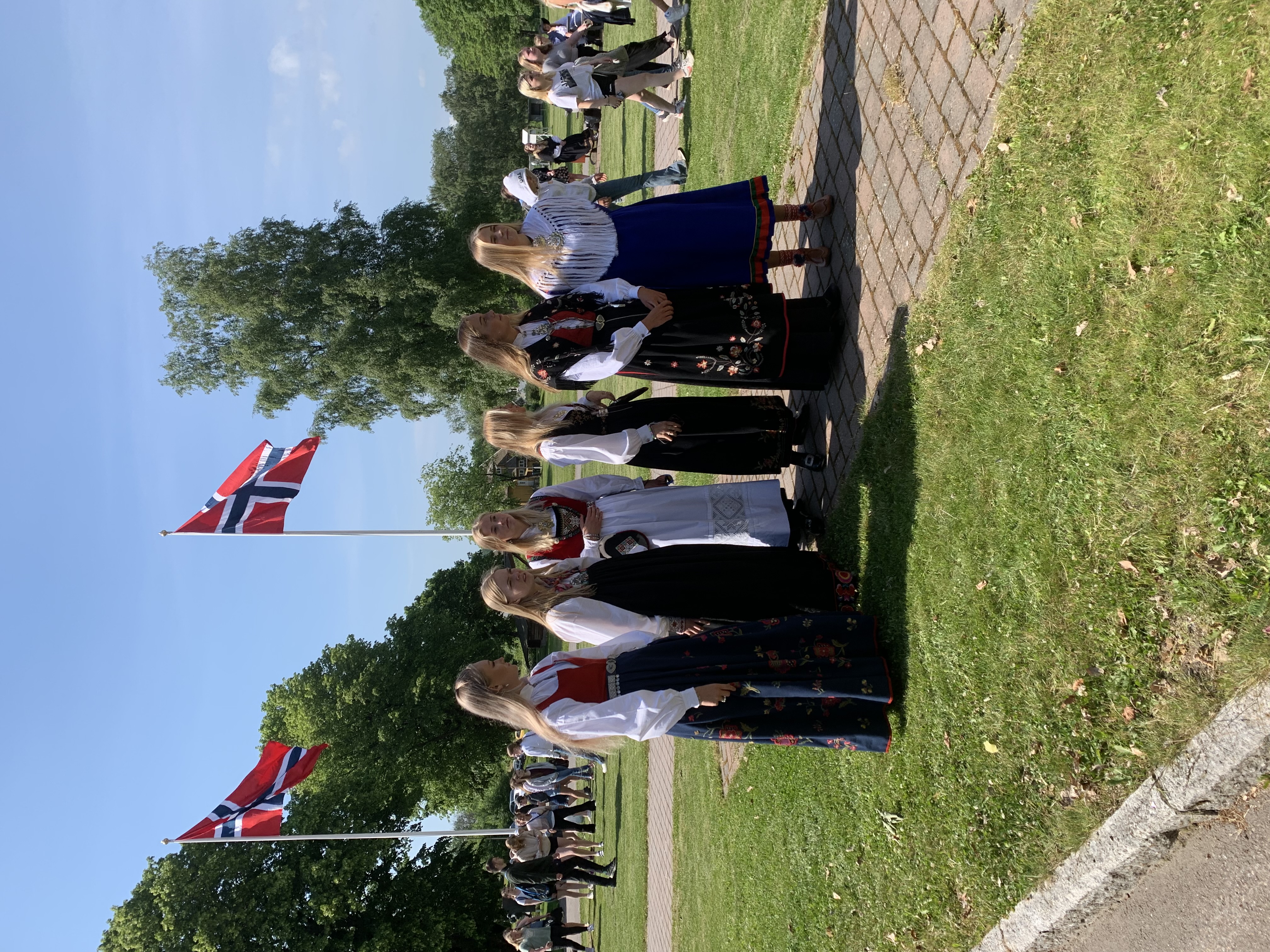Bunadkledde elever og norske flagg på plenen utenfor skolen