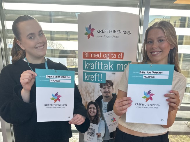 To jenter holder opp plakater for kreftforeningen.