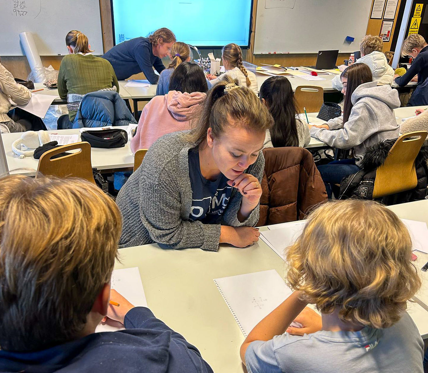 Lærer hjelper elever med skoleoppgaver.