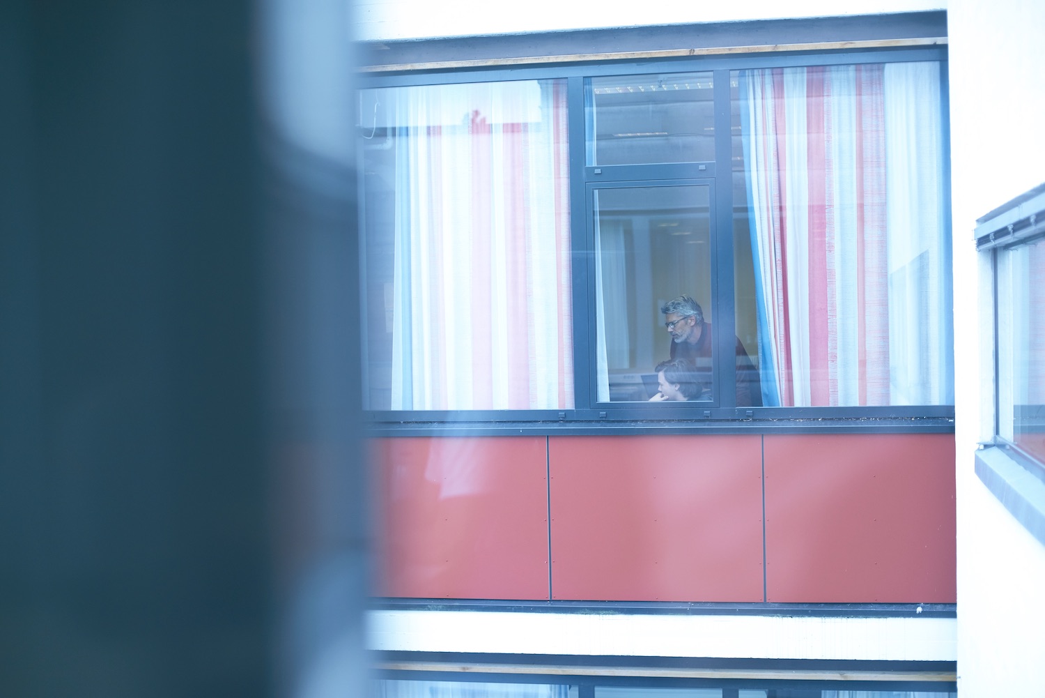 Bilde av lærer og elev bak et vindu