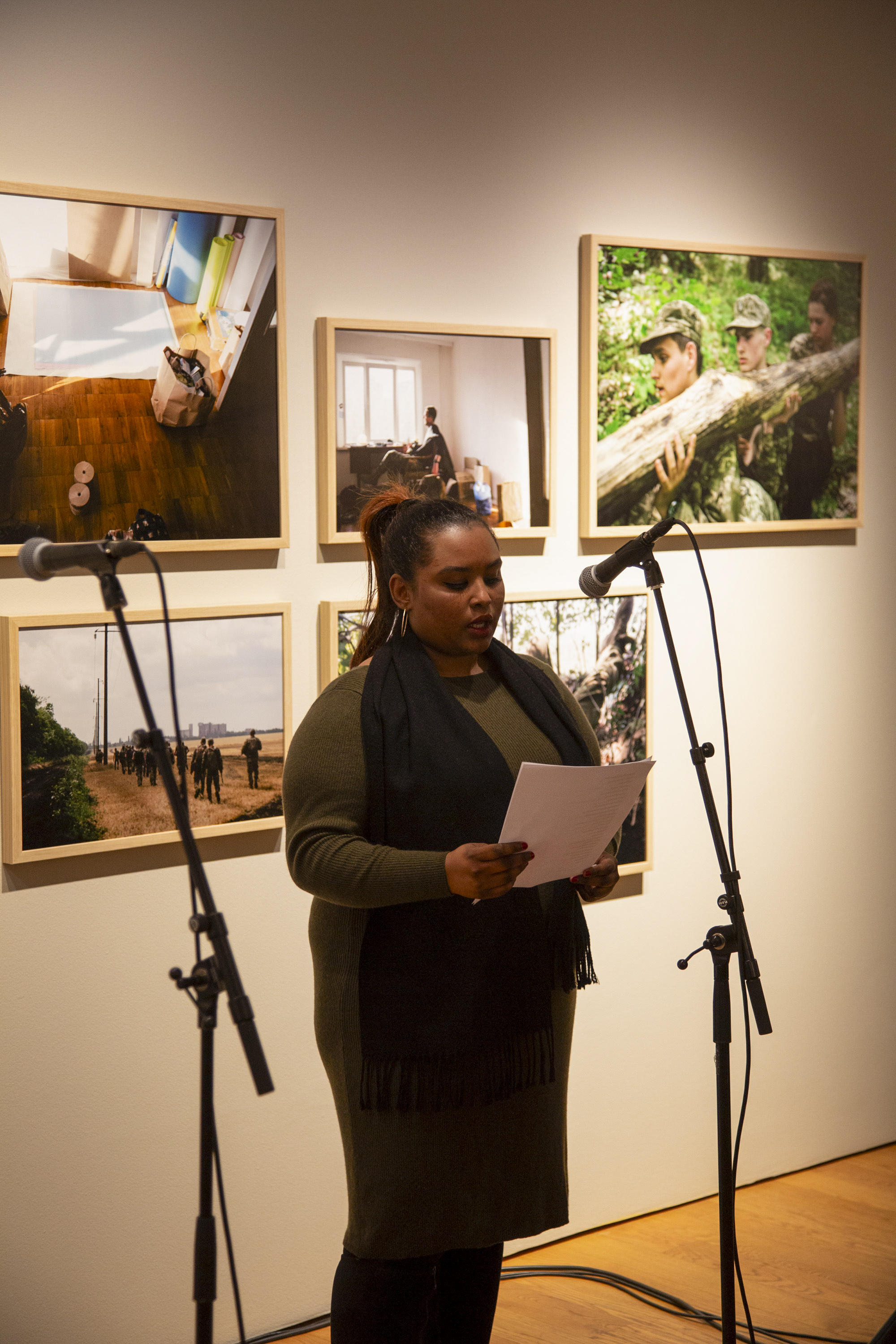 Kvinne leser tekst foran mikrofon ved åpning av utstillingen