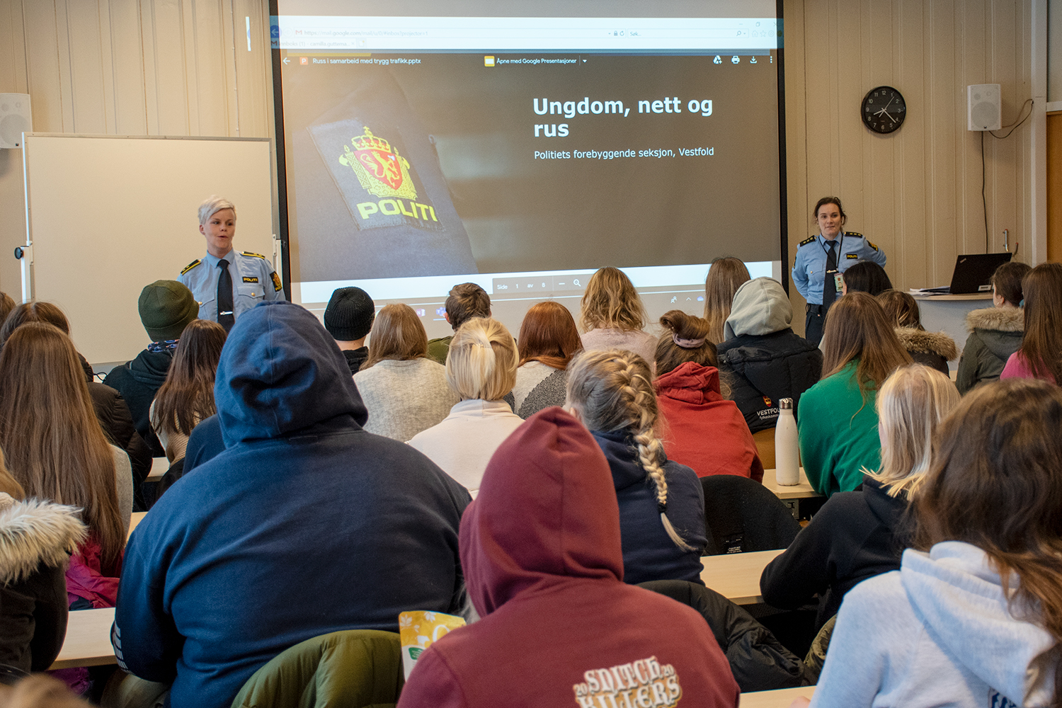 Elever i klasserom ser presentasjon som to politi holder