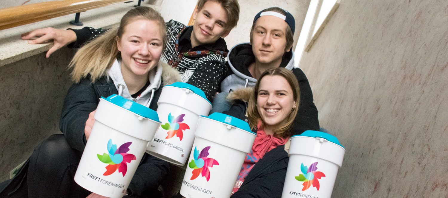 Fire elever holder innsamlingsbøsser foran seg