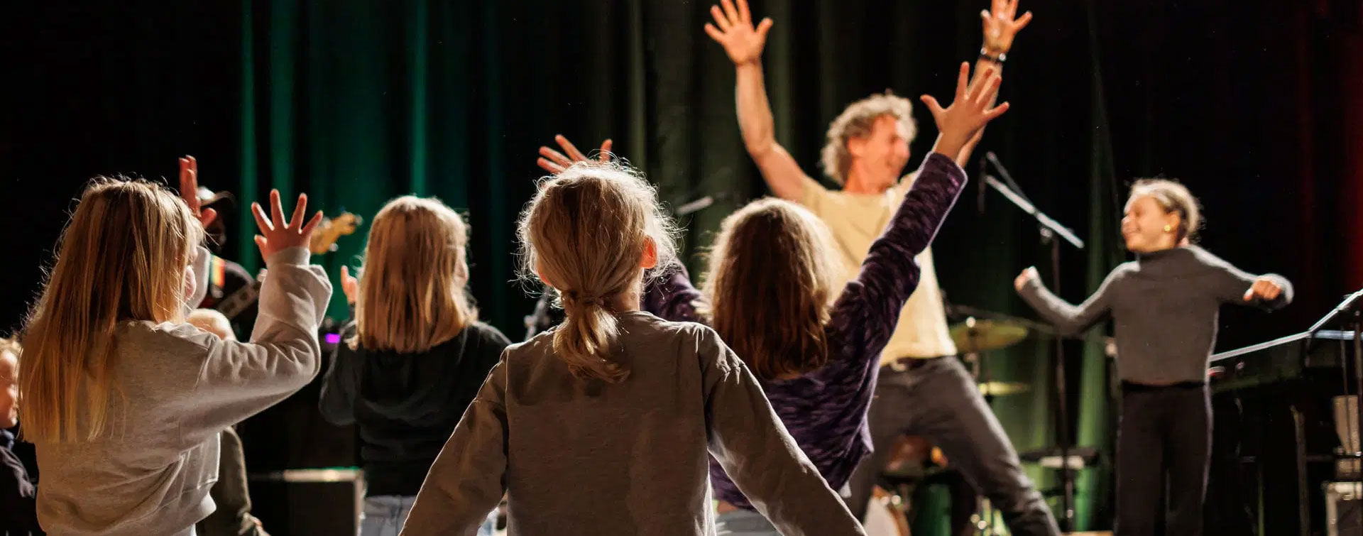 Barn foran scene med henda til væres