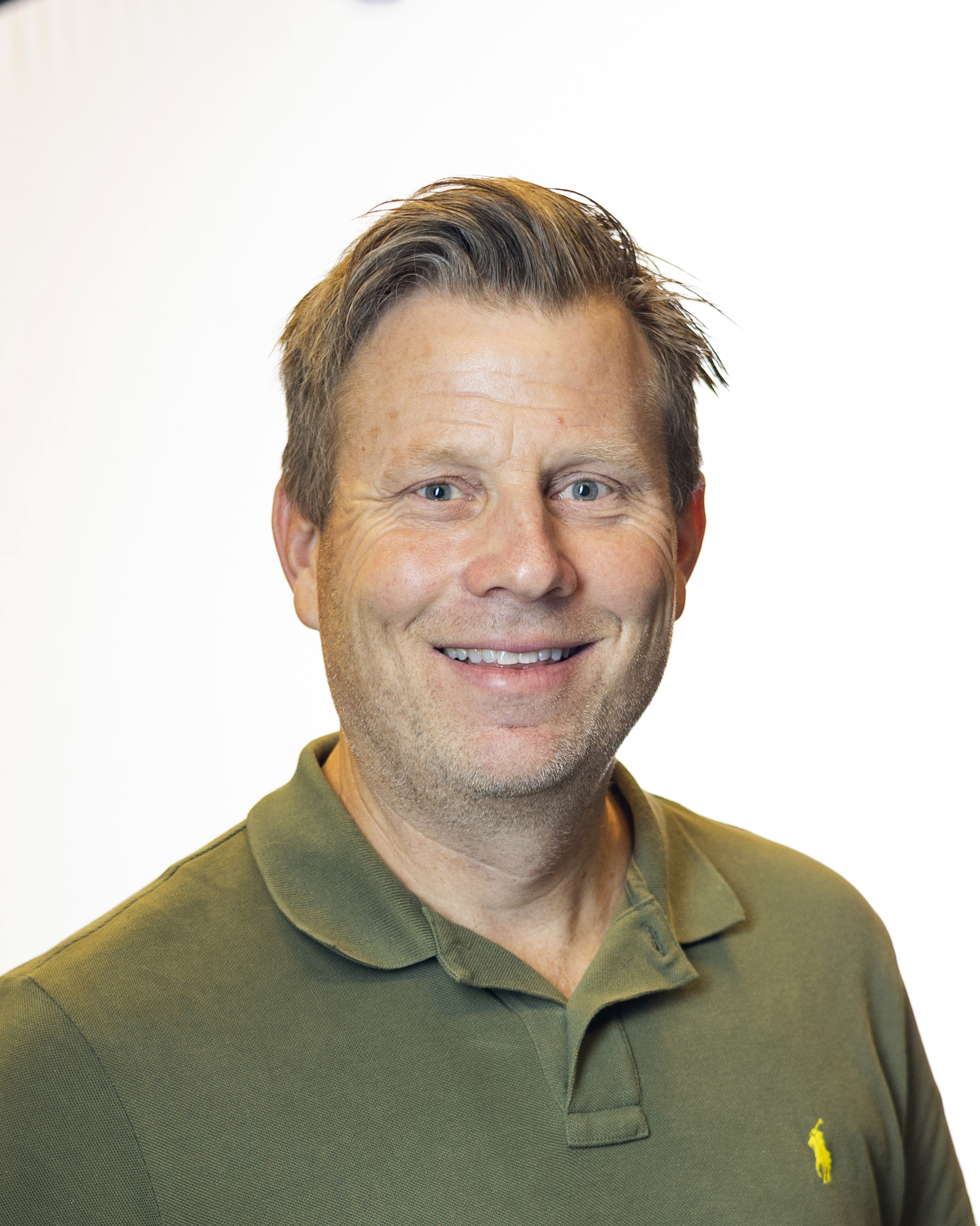 Mann med kort hår og grønn piké t-skjorte.
