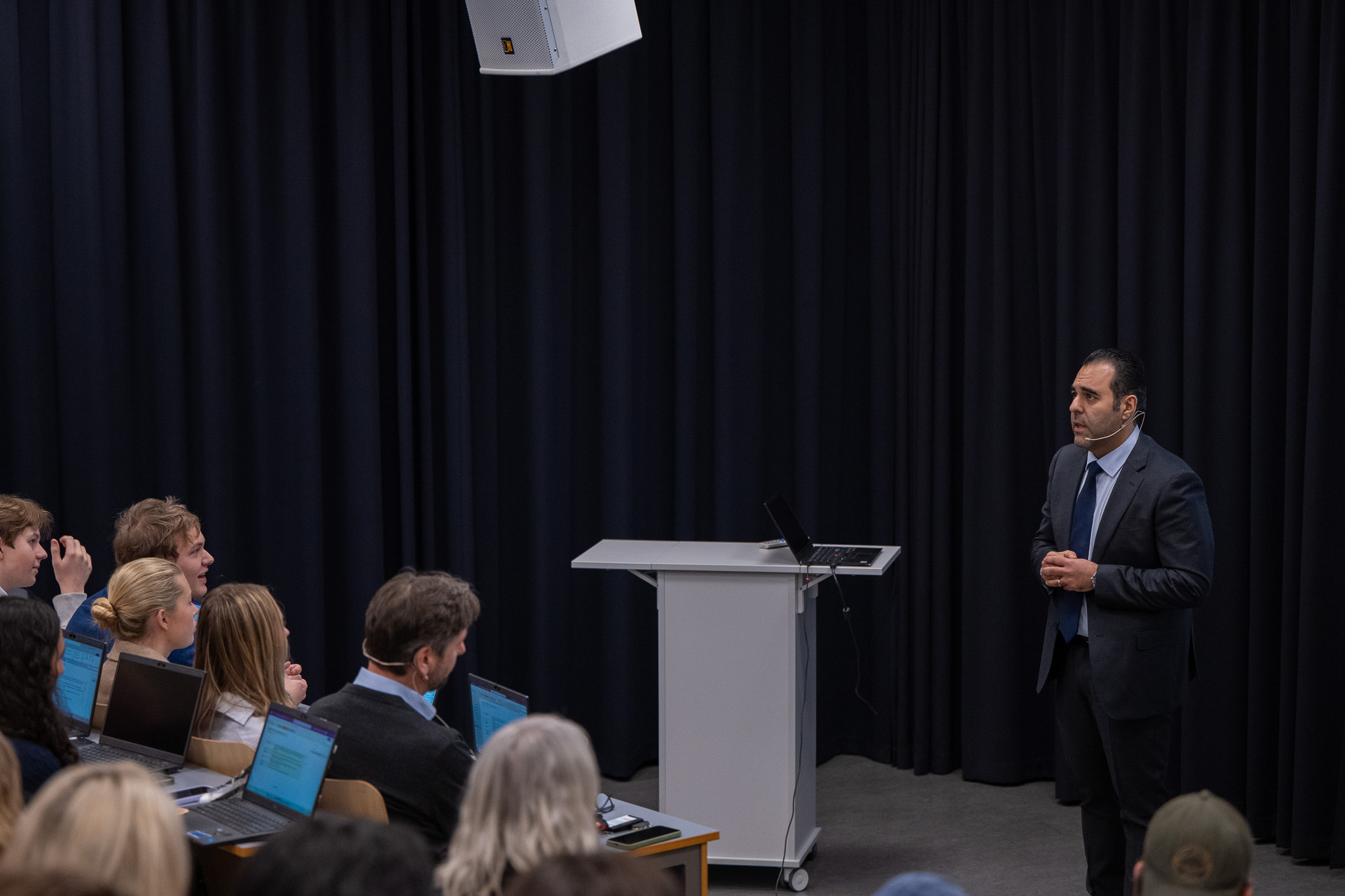 Mann på scene i mørk dress