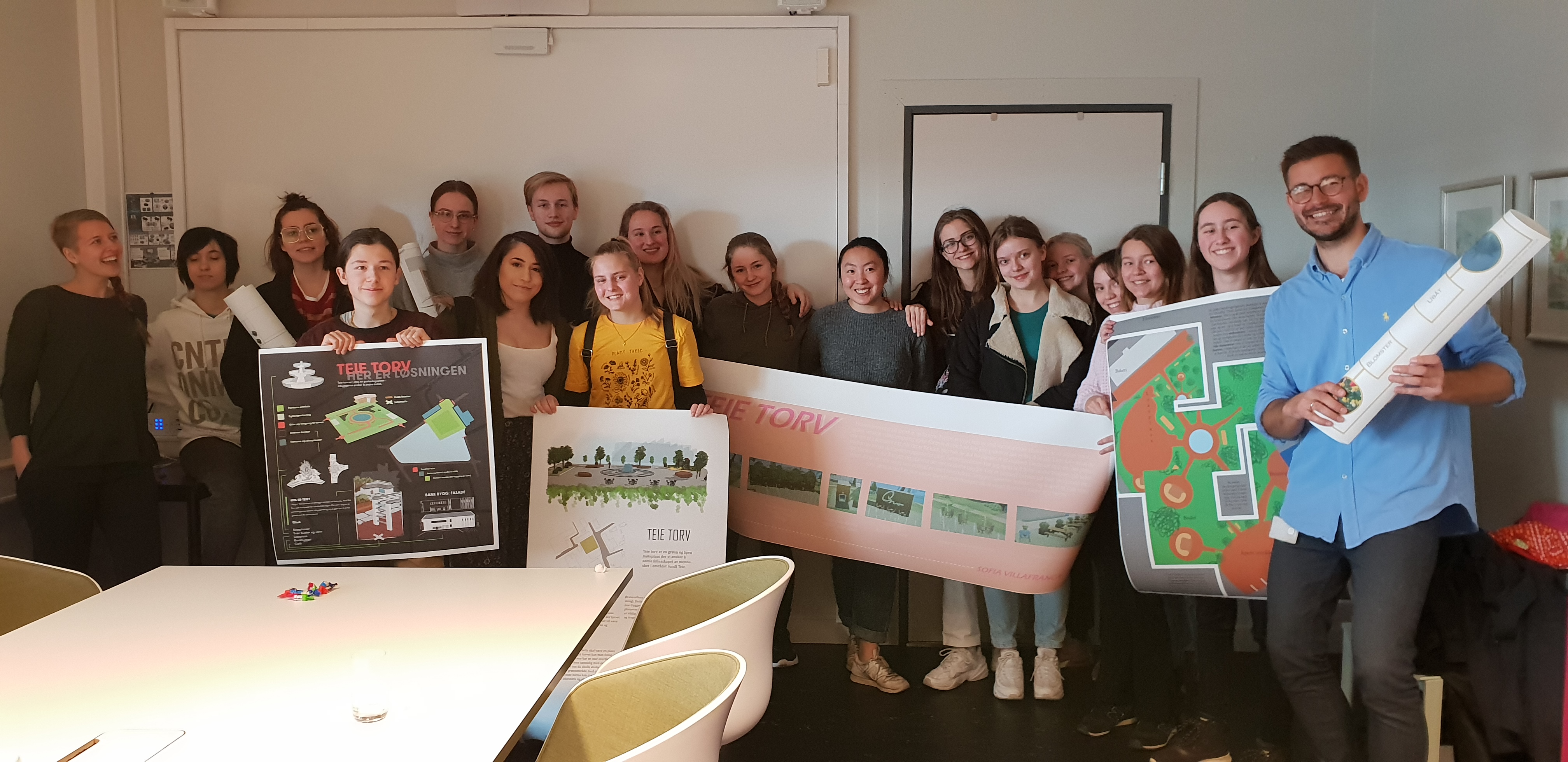 Foto av elever ved Færder videregående som holder tegninger som viser hvordan de ser for seg Teie torv i fremtiden