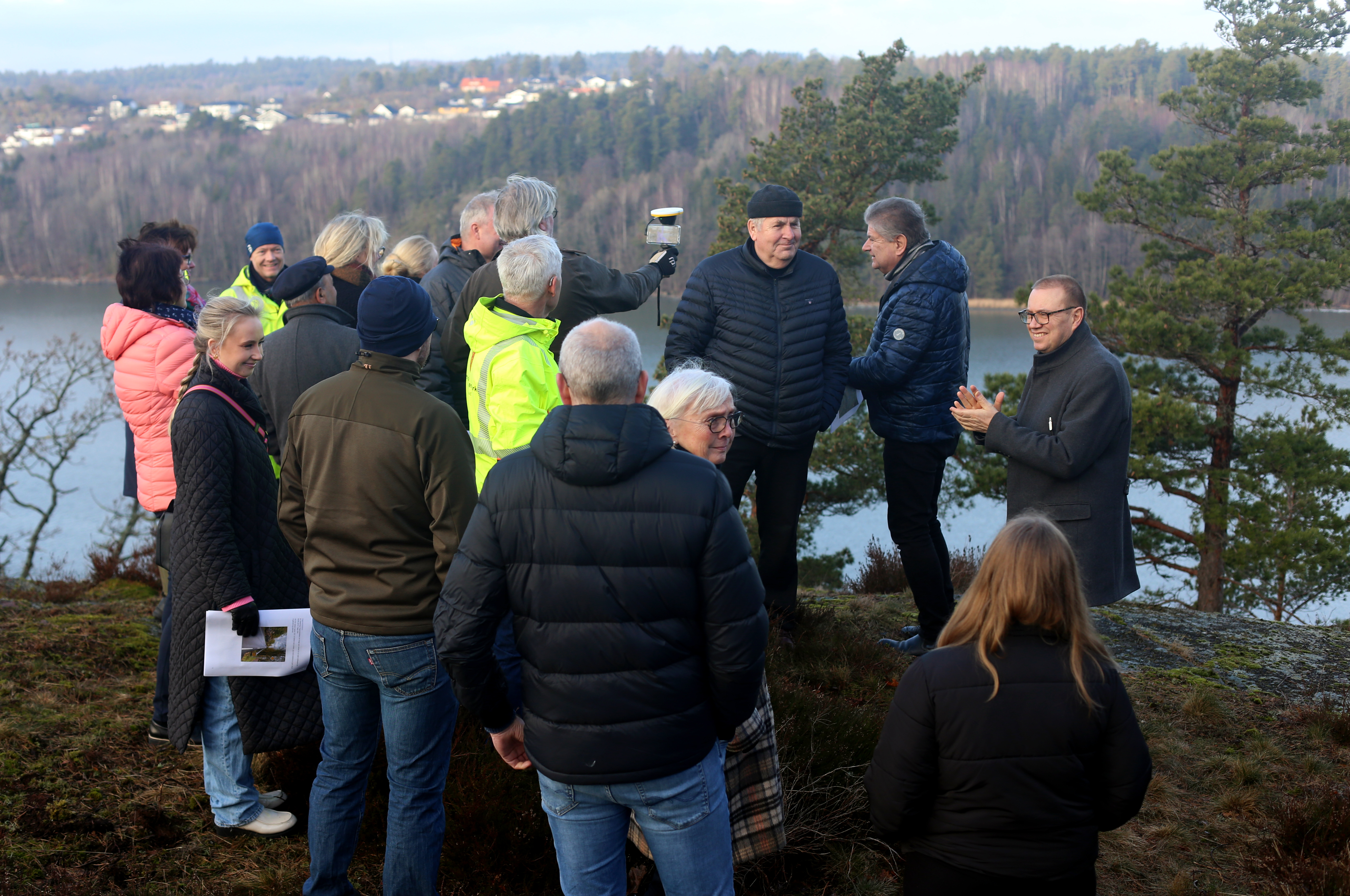 Representanter for hovedutvalget står foran punktet der den nye brua skal ligge. Fjorden og Smørberg skimtes i bakgrunnen.