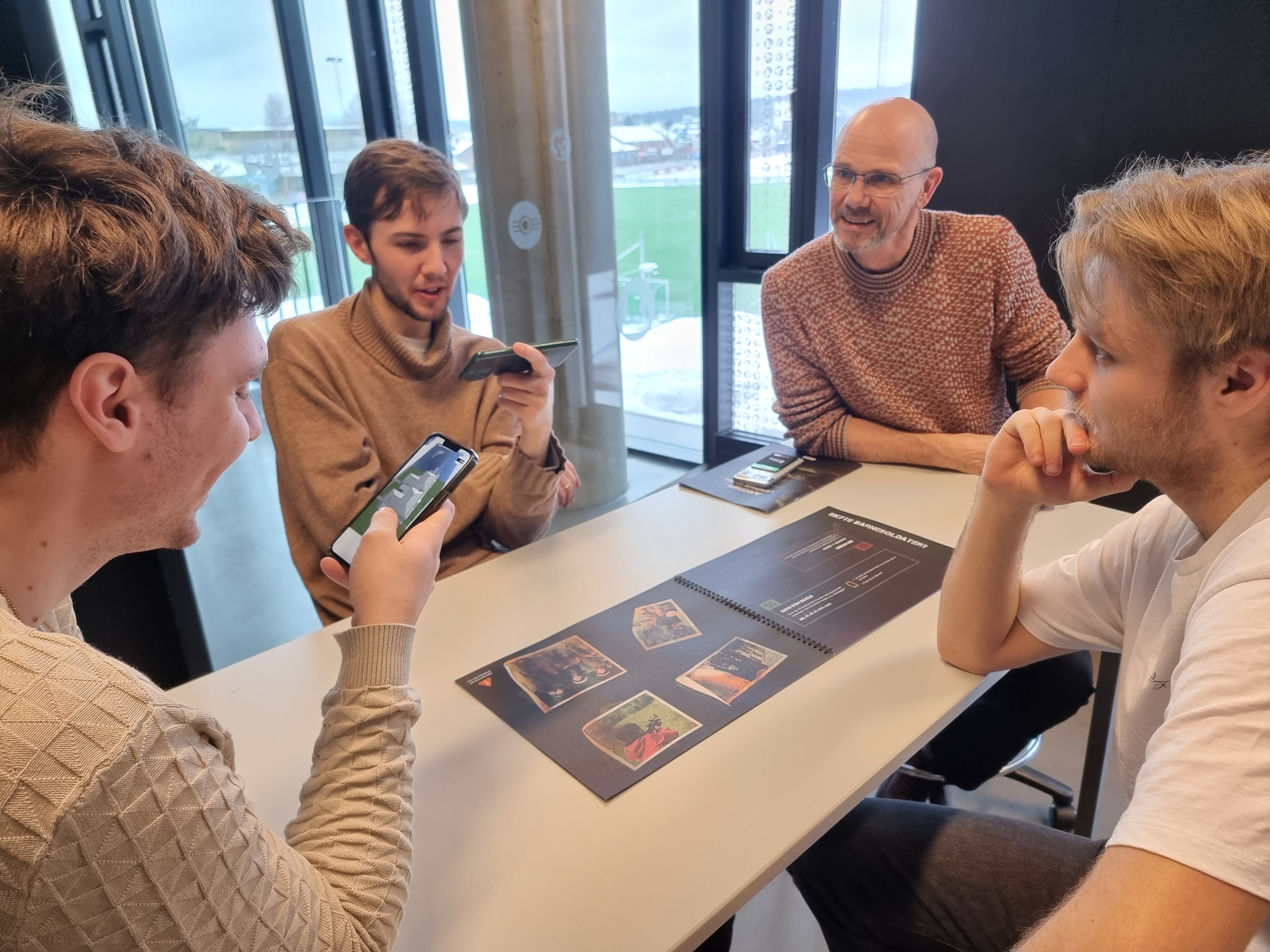 Tre stunder og lærer sitter med brettspill rundt et bord.