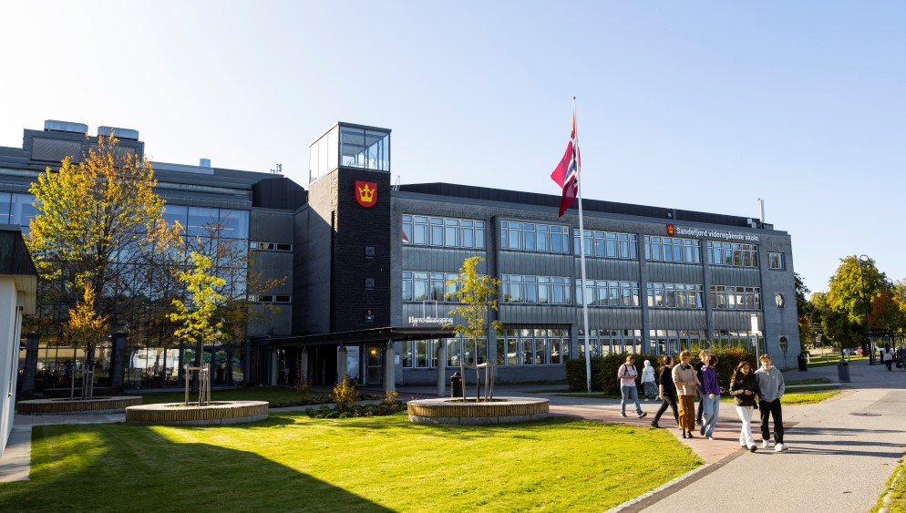 Skolens hovedinngang, flaggstang med norske flagg.