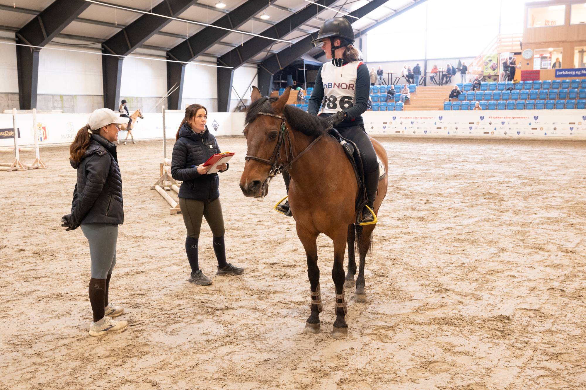 Elev på hest snakker med to trenere