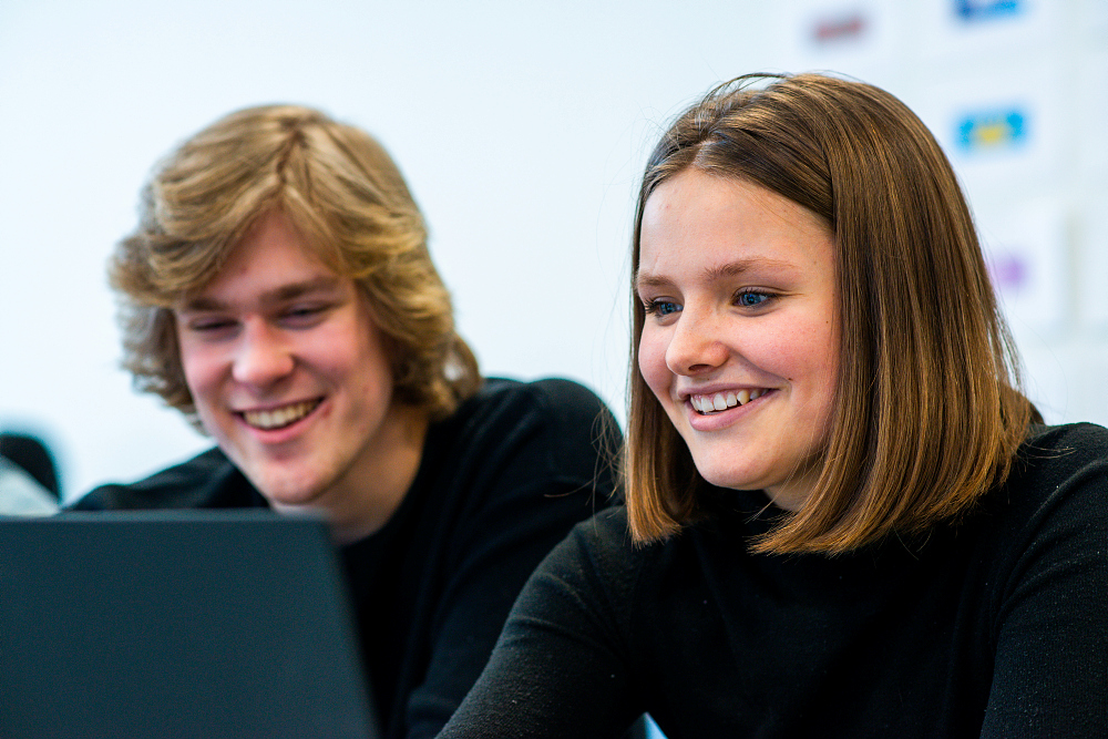 Jente og gutt ser på laptop