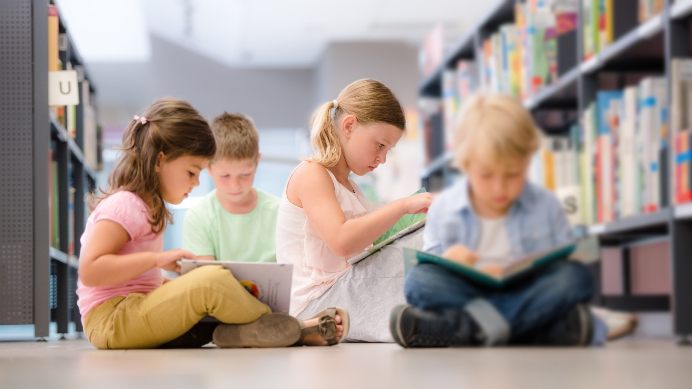 Barn som sitter på gulvet i et bibliotek