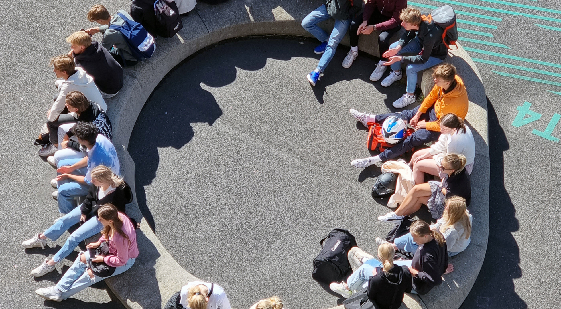 Elever sitter i en ring på en steinblokk.