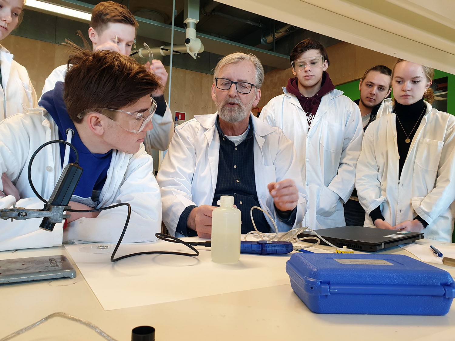 Elever ser en lærer demonstrere et forsøk i kjemi